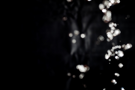 Photo of bokeh water splash black background with copy spaceの写真素材