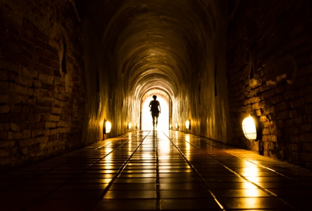 silhouette of human in old brick tunnel light at end of tunnelの写真素材