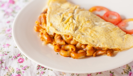 Fried macaroni with tomato sauce wrapped with omelette thai foodの写真素材