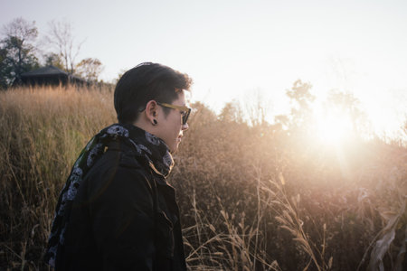 Vintage photo portrait of young man with sunrise in grass field morning timeの写真素材
