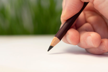 A male hand draws with a pencil on a piece of paper. artistic tool. Idea, hobby and creativity....
