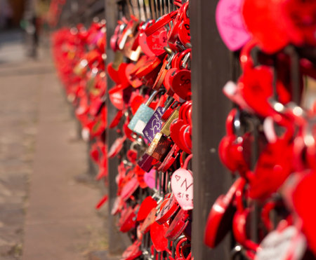 Locked red locks of lovers on an iron fence. Symbol of love and marriage. Romantic custom....
