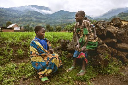 Byumba, Rwanda, Africa - September 6, 2015: Unidentified kids. The kids wearing traditional clothes sitting grasses. One of these children carries his sister by a cloth which is tied behind his back.のeditorial素材