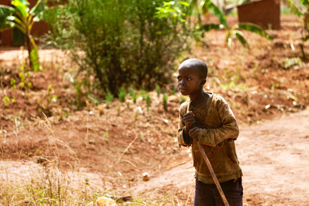 Kibuye, Rwanda, Africa - September 11, 2015: Unknown child. The farmer African child with his stick look across. He works in banana and coffee fields. There is a banana tree behind him.のeditorial素材