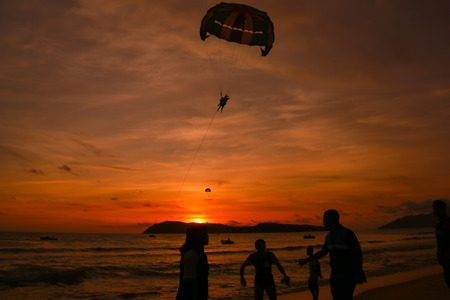 silhouette of parachute and peoples above the sunsetの写真素材