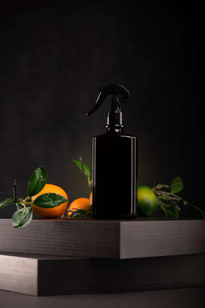 Bottle of liquid soap on wooden stand with citrus fruits on black backgroundの写真素材