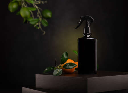 Bottle of black liquid soap with green leaves and orange on black backgroundの写真素材