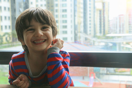 A cute boy laughs from his balcony, overlooking the garden.