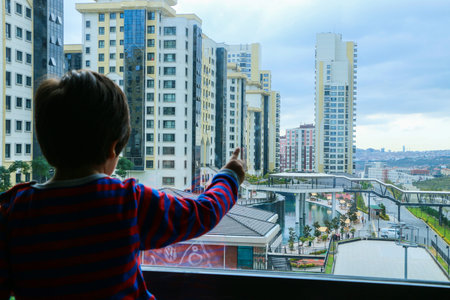 Child looks at the towers from the balcony of the house. Huge residential towers