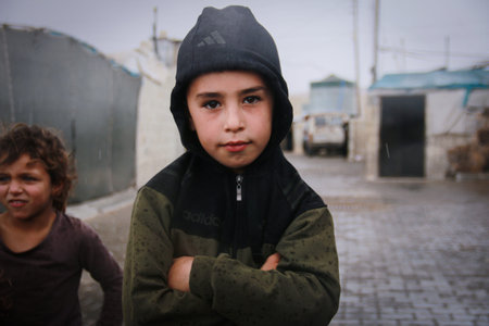 A Syrian refugee child during the rain, refugees in the winter.
Aleppo, Syria October 17, 2021
