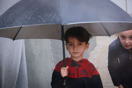 Little refugee children with umbrella in the rain,  refugee with umbrella.
Aleppo, Syria October 17, 2021のeditorial素材