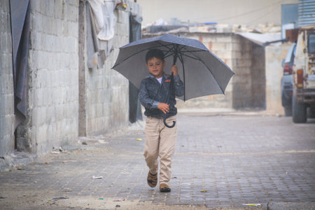Little refugee children with umbrella in the rain,  refugee with umbrella.
Aleppo, Syria October 17, 2021のeditorial素材
