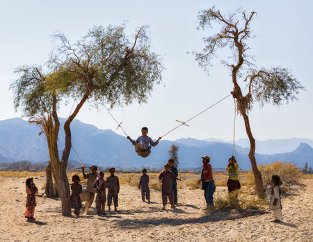 Baloch children (Baluch) playing next to their traditional houses in Nikshahr County, Sistan and...