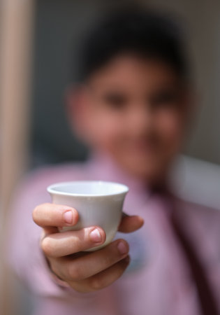 bokeh photo of boy carries a cup of arabic coffeeの写真素材