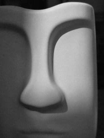 A close-up of a minimalist white sculpture resembling a face, with soft shadows highlighting its features. The smooth surface creates a serene and abstract appearance.の写真素材