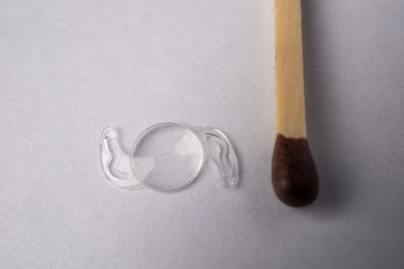 Close-up of a contact lens next to a matchstick on a white surface.の写真素材