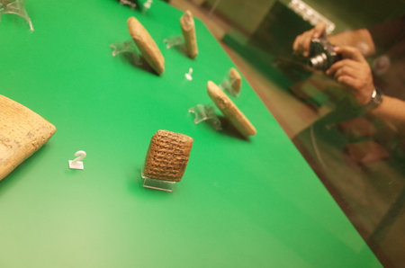 Ancient artifacts displayed on a green table, showcasing historical significance, with a camera in the background capturing the sceneのeditorial素材