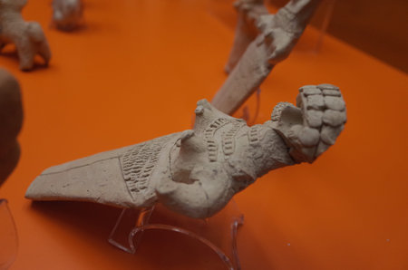 A clay figurine depicting a seated figure with intricate details, possibly an ancient artifact,...