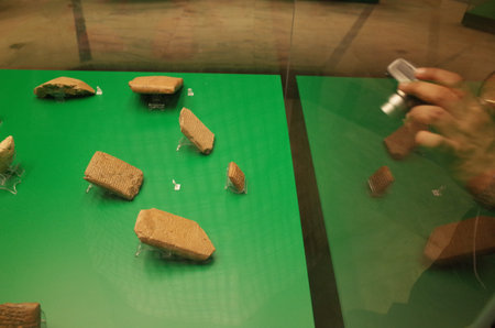 Ancient artifacts displayed in a museum, featuring rectangular stone tablets with inscriptions, set...