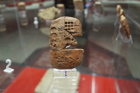 Ancient clay tablet with inscriptions, displayed in a museum case, showcasing historical artifacts