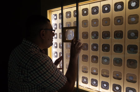 A person examining a display of circular objects through a magnifying glass, showcasing curiosity...