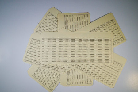 A collection of vintage punch cards arranged in a circular pattern on a light surface. Each card...