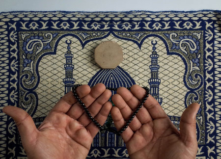 praying with hands and rosary on prayer carpetの写真素材