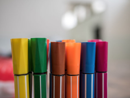 A close-up of colorful markers arranged in a row, showcasing vibrant caps in various colors, with a blurred backgroundの写真素材