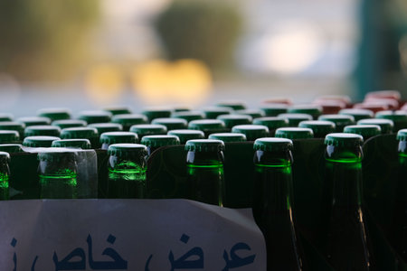 A close-up view of green glass bottles arranged in rows, with a blurred background, showcasing a...