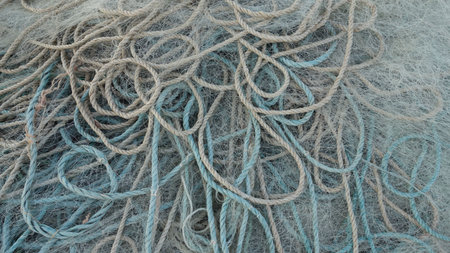A close-up view of tangled fishing nets and ropes, showcasing various textures and colors,...