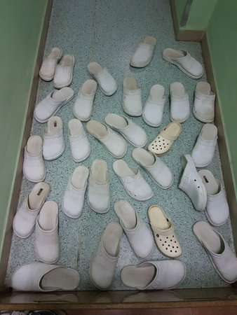 A collection of white shoes scattered on a tiled floor