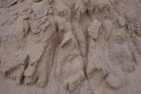 A close-up view of a sandy surface with textured patterns resembling natural formations