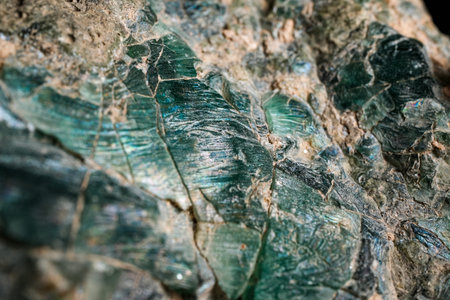 Macro close-up of rough mineral rock with green-blue crystalline veins and textured stone surface;...