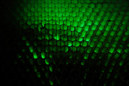 Abstract macro of glowing green honeycomb hexagon pattern, futuristic texture background with depth...