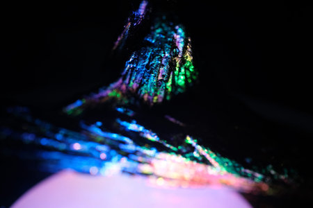 Macro photograph of iridescent mineral or rock fragment with blue, green and purple metallic sheen...