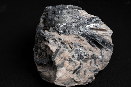 Rough rock specimen with metallic silver-black bladed crystals set in pale gray matrix,...