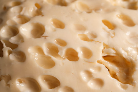 Close-up of creamy swiss cheese surface with holes and smooth textureの写真素材
