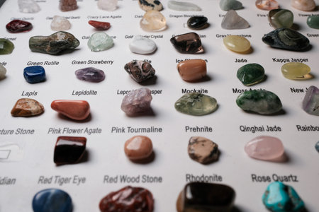 Sorted collection of polished gemstone samples labeled on a white board, photographed at shallow...