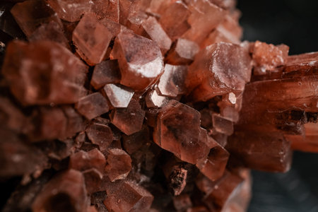 Macro close-up of reddish brown mineral crystal cluster with hexagonal prisms, rough texture, and dark blurred background, ideal for geology, gemstone, and natural texture concepts.の写真素材