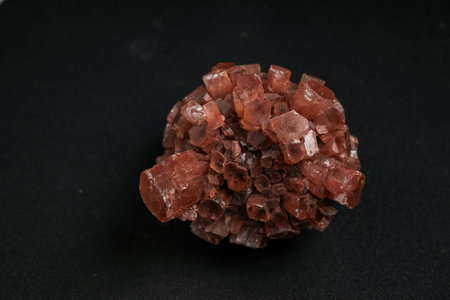Cluster of reddish-brown cubic crystals on black background, mineral specimen photographed top-down