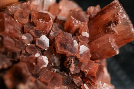 Macro close-up of red-brown crystal cluster with translucent faceted mineral prisms and sparkling highlights on dark background, natural geology texture for gemstone and science themes.の写真素材