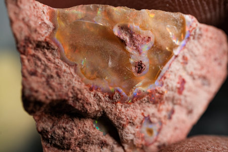 Macro close-up of rough opal in host rock with iridescent flashes and pinkish matrix, natural...