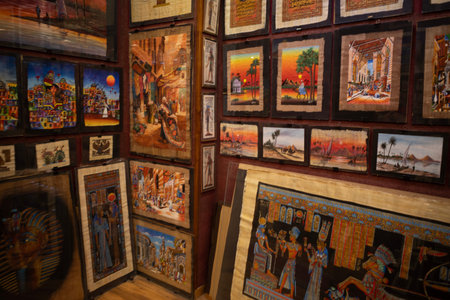 Vibrant display of egyptian-style paintings and papyrus art hung on walls and stacked in a shop cornerのeditorial素材