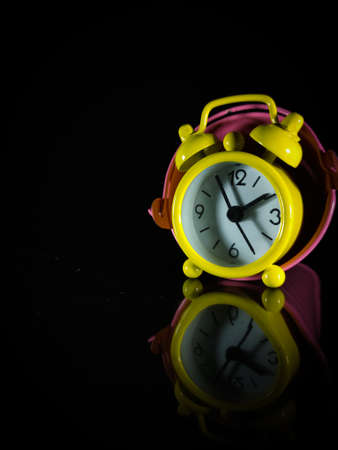Selective focus.A yellow clock inside the bucket with reflection on a black background.Shot were noise and film grain.の写真素材