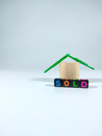 Selective focus.Word SOLD from black dice with simple house on a white background.Property concept idea.Shot were noise and film grain.の写真素材