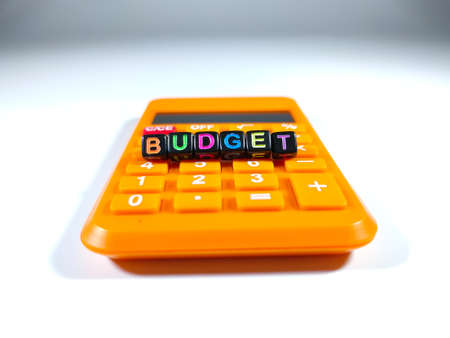 Selective focus.Word BUDGET from a black dice with calculator on white background.Shot were noise and film grain.の写真素材