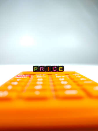 Selective focus.Word PRICE from a black dice with calculator on a white background.Shot were noise and film grain.の写真素材
