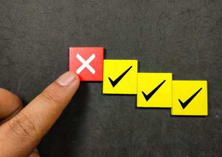 Someone finger show the wooden cubes with right and wrong marks. The concept of check marksの写真素材