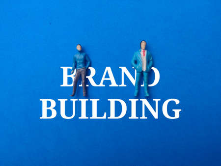 Top view pair a wooden doll protect with a red umbrella on a green background with copy space text. The concept of insurance coverage.の写真素材