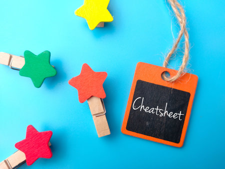Colored wooden tag and wooden clips with text Cheatsheet on blue background.の写真素材